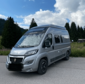 Van aménagé gris stationné en montagne