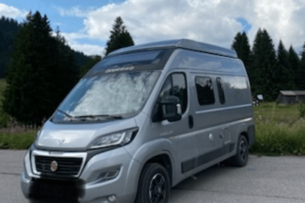 Van aménagé gris stationné en montagne