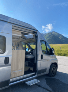 Van aménagé ouvert face aux montagnes verdoyantes