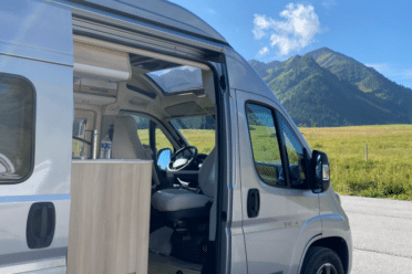 Van aménagé ouvert face aux montagnes verdoyantes