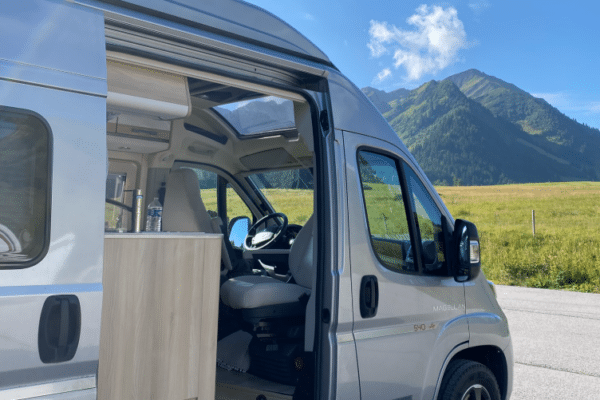 Van aménagé ouvert face aux montagnes verdoyantes