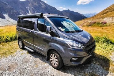 Van aménagé gris en montagne ensoleillée