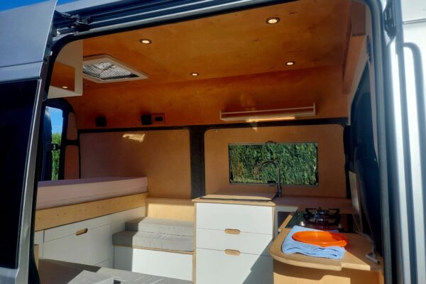 Intérieur aménagé de van avec kitchenette et lit