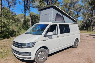 Campervan weiß mit Aufstelldach im Wald