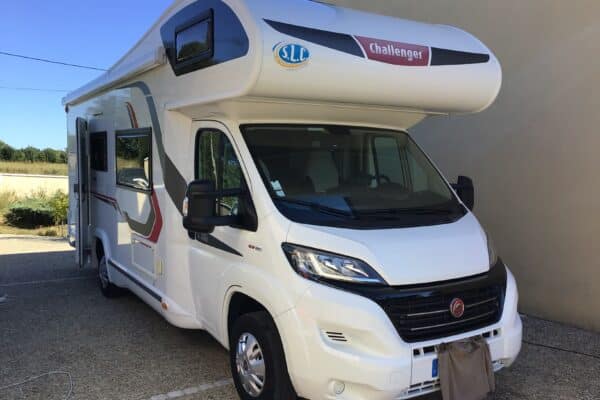 Camping-car Challenger blanc stationné près d’un bâtiment