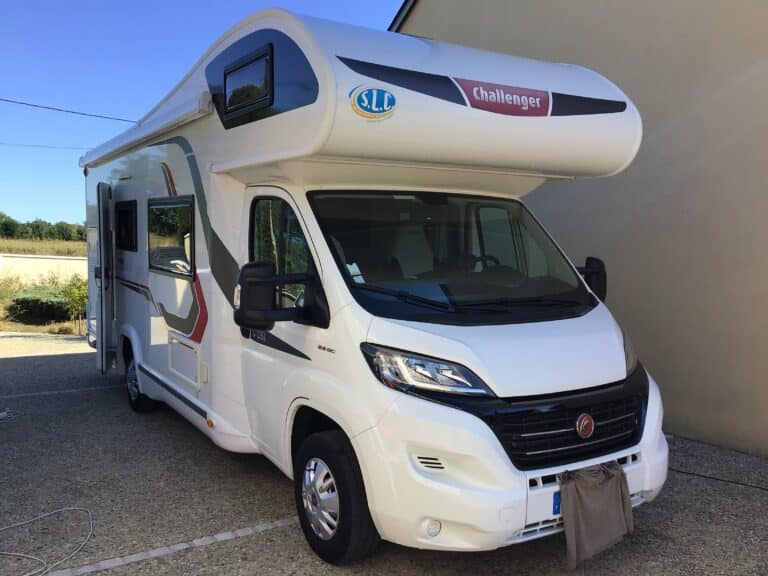Camping-car Challenger blanc stationné près d’un bâtiment