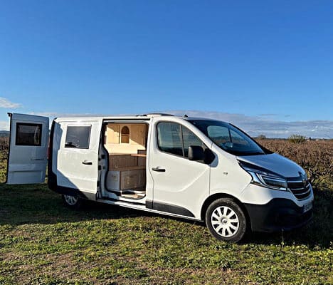Van aménagé blanc stationné en pleine nature