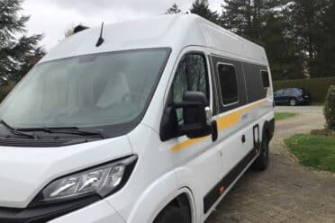 Furgone camperizzato bianco parcheggiato nel vialetto asfaltato
