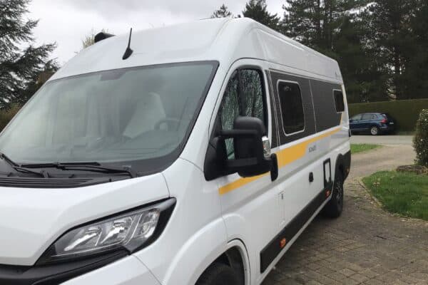 Fourgon aménagé blanc stationné dans une allée pavée