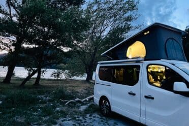 Van aménagé au bord d’un lac au crépuscule