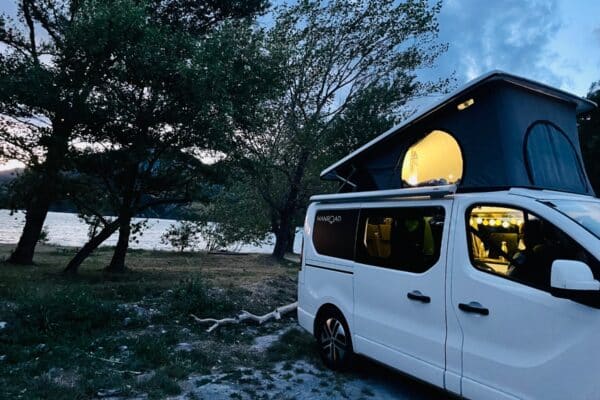 Van aménagé au bord d’un lac au crépuscule