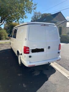 Arrière d’un van blanc stationné en rue