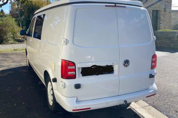 Arrière d’un van blanc stationné en rue