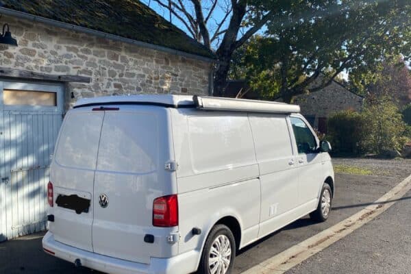 Fourgon Volkswagen blanc stationné près maison en pierre