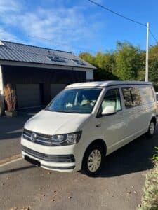 Van Volkswagen blanc garé devant maison moderne