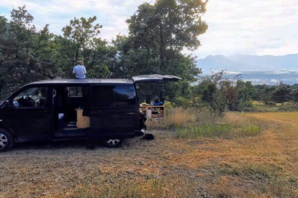 Van aménagé noir garé face aux montagnes