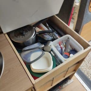 Tiroir de cuisine encombré avec casseroles et boîtes