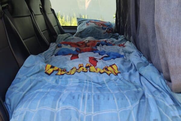 Lit aménagé dans van avec draps Spider-Man