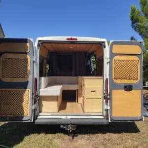 Intérieur aménagé d’un van avec banquettes en bois