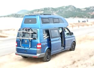 Van aménagé bleu garé sur plage