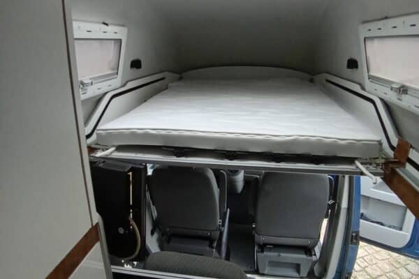 Lit surélevé dans van aménagé avec lanterneau
