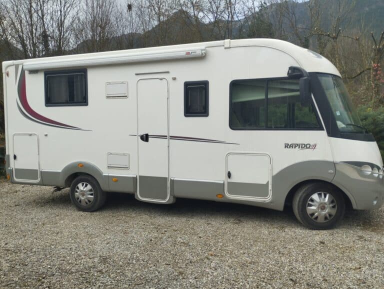 Camping-car blanc stationné sur terrain gravillonné