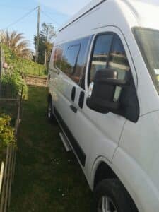 Fourgon aménagé blanc garé dans un jardin