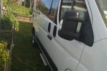 Fourgon aménagé blanc garé dans un jardin