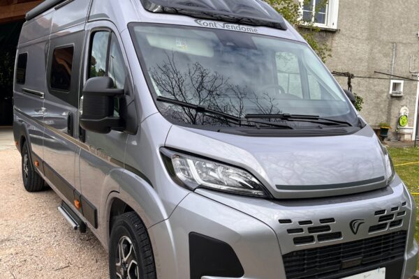 Fourgon aménagé gris stationné devant une maison