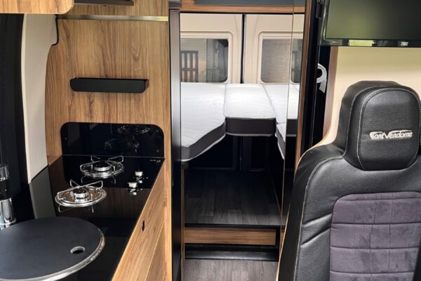 Intérieur de van aménagé avec cuisine et lit arrière