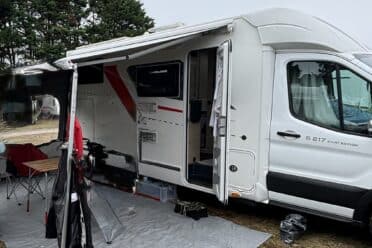 Camping-car blanc avec auvent et table extérieure