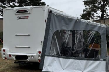 Camping-car avec auvent fermé sur terrain herbeux