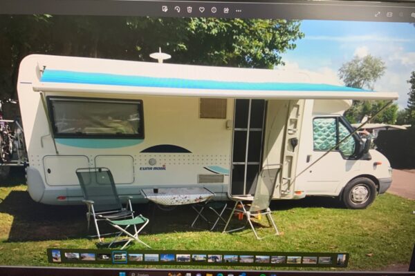 Camper bianco con tenda da sole e mobili da esterno