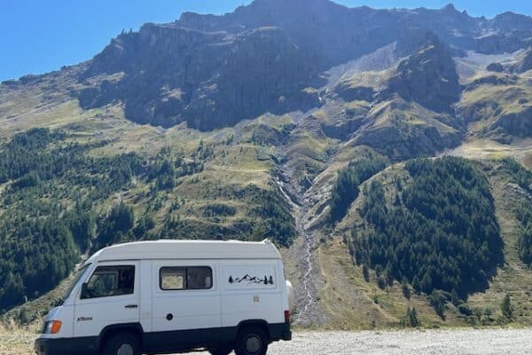 Van blanc devant montagnes et forêt alpine