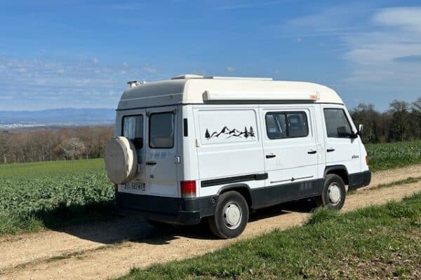 Fourgon aménagé blanc sur chemin de campagne