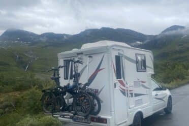 Wohnmobil mit Fahrrädern vor nebliger Berglandschaft