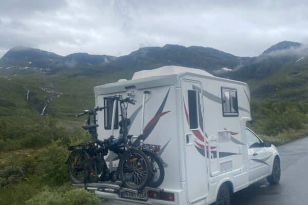 Wohnmobil mit Fahrrädern vor nebliger Berglandschaft