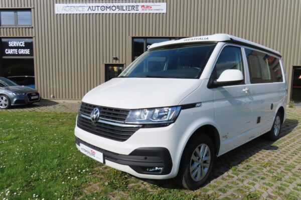 Van Volkswagen Westfalia blanc devant concession automobile