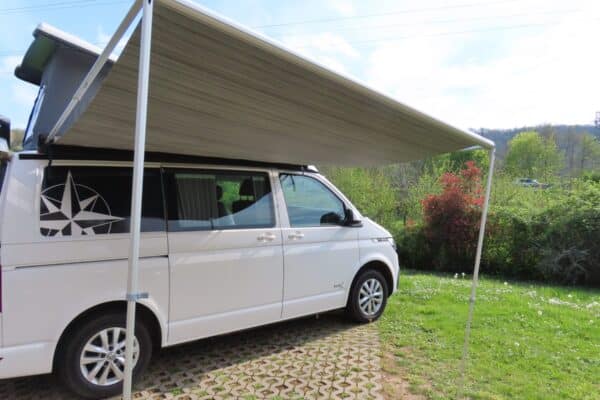 Van aménagé blanc avec auvent déployé au camping