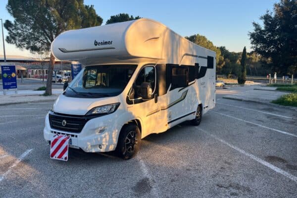 Camping-car blanc stationné sur un parking ensoleillé