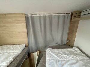 Petite chambre avec deux lits simples et rideau