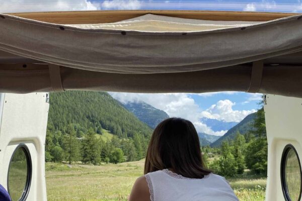 Femme admirant vallée montagneuse depuis van aménagé