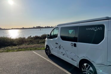 Van camperizzato parcheggiato di fronte al mare al tramonto