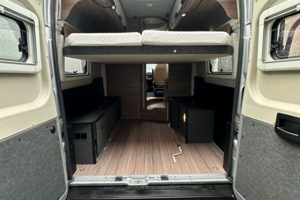 Interno di camper con letto rialzato e vani