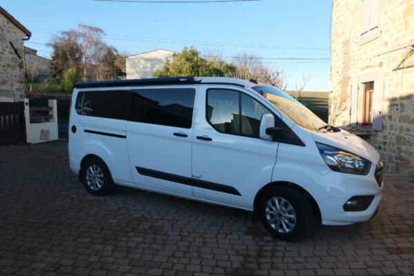 Van aménagé blanc stationné dans cour pavée