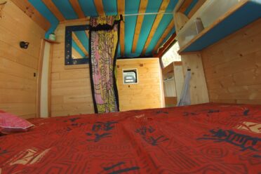 Intérieur bois d’un van aménagé avec lit rouge
