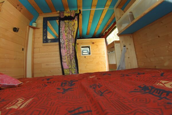 Intérieur bois d’un van aménagé avec lit rouge