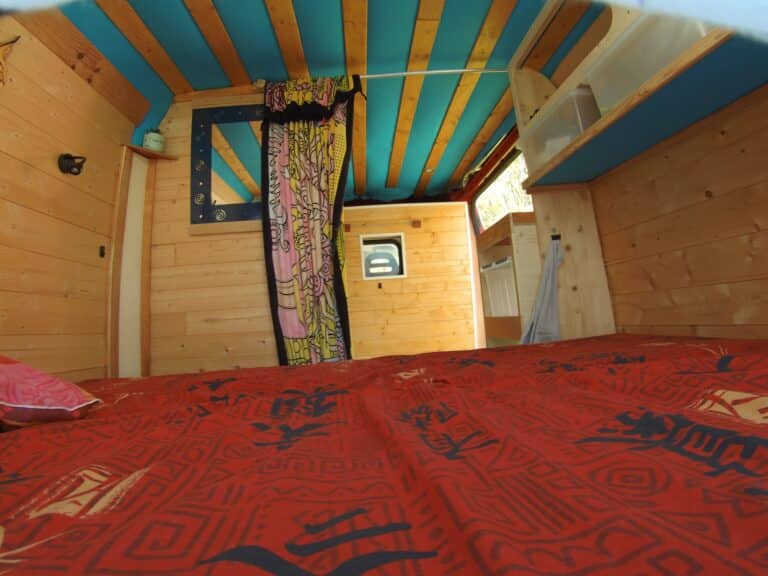 Intérieur bois d’un van aménagé avec lit rouge