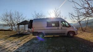 Fourgon aménagé stationné face aux montagnes au coucher du soleil