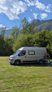 Van aménagé stationné face aux montagnes verdoyantes